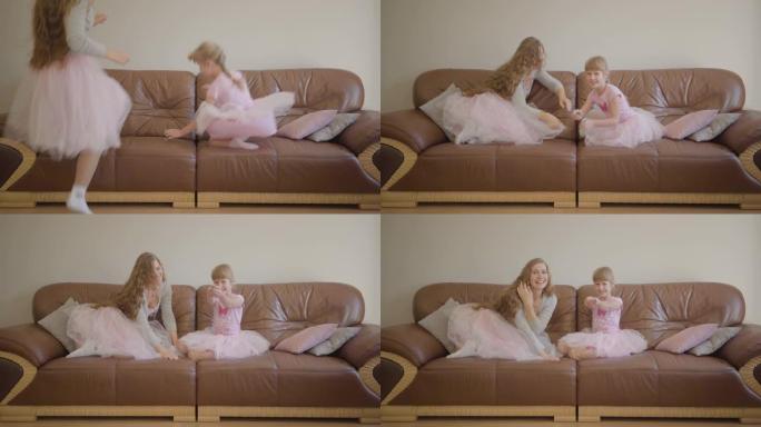 快乐的高加索妈妈和女儿穿着同样的粉红色连衣裙跳上教练，打开电视