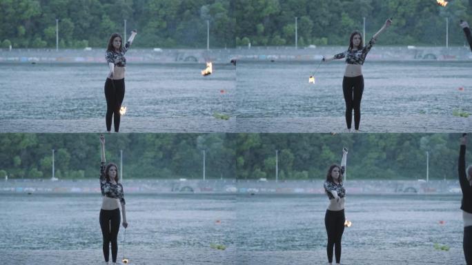 两名年轻女子站在河岸上表演火焰球。
