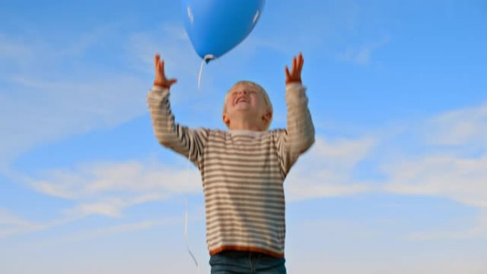SLO MO金发小男孩放开气球，仰望天空