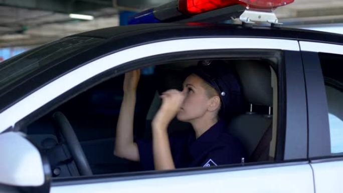 负责任的女警戴着服务帽坐在巡逻车上值班