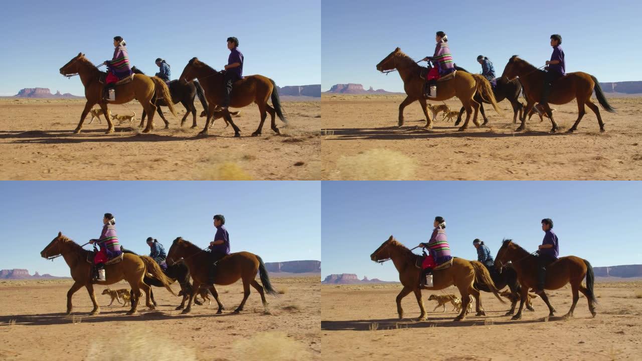 在晴朗明亮的日子里，几名年轻的美国原住民 (纳瓦霍人) 的孩子骑着马穿过纪念碑谷沙漠，带着他们的宠物