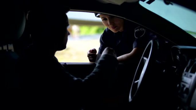 友好的女警察检查汽车男子的驾驶执照，道路检查