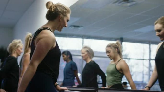 一群多种族的不同年龄的妇女在健身室的大镜子前的芭蕾舞中站起来伸展