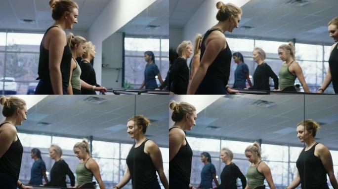 一群多种族的不同年龄的妇女在健身室的大镜子前的芭蕾舞中站起来伸展