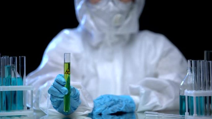 有毒实验室工作人员用绿色电离辐射液体拿着试管