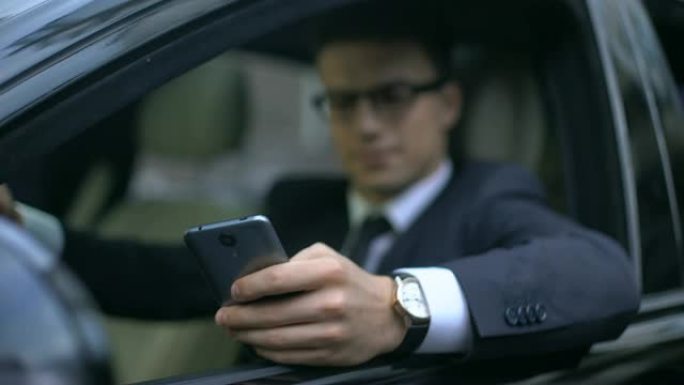 认真的商人在车上等待时在电话上测试新的业务应用程序