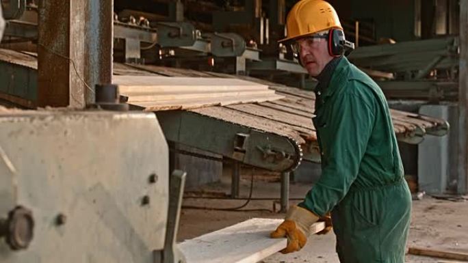 在锯木厂经营木材磨边机的男工人