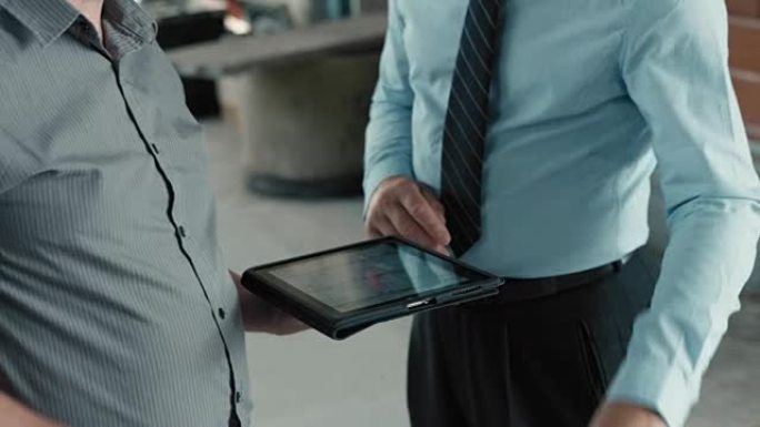 男性建筑师和项目经理将桌子上的计划与数字平板电脑上的计划进行比较