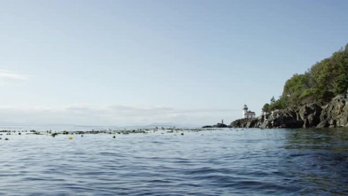 在华盛顿州圣胡安岛附近的晴天，远处的石灰窑灯塔在星期五港口荡漾的慢动作镜头