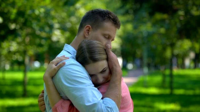男人在公园拥抱和安慰沮丧的女友，团结和支持