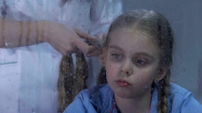 医务人员编织不舒服的女孩头发，孩子在医院里想家
