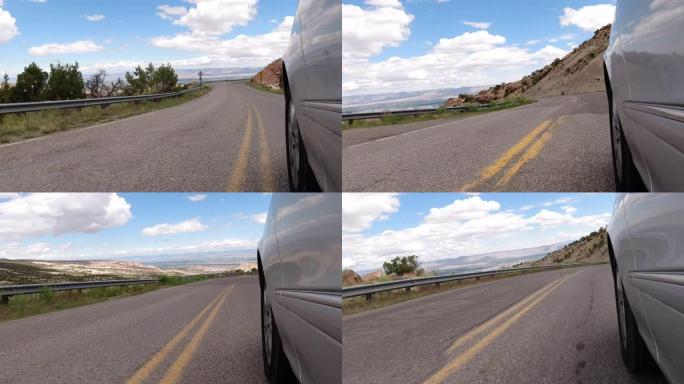 在部分多云的天空下，在科罗拉多州弗鲁伊塔和大章克申驾驶科罗拉多国家纪念碑时，从银色车辆的侧面看