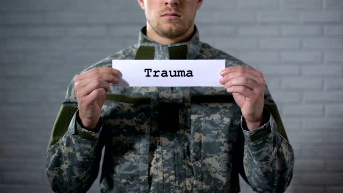 男性士兵手中的标志上写的创伤字，对身体的伤害，健康