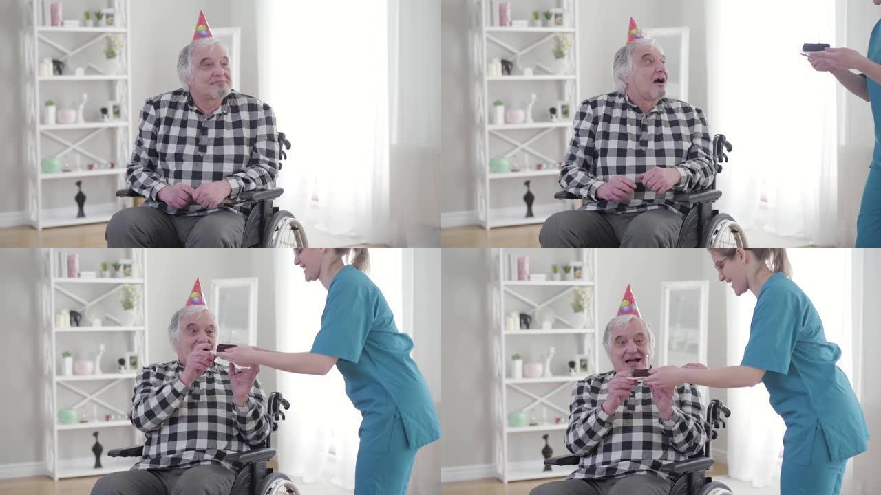 坐在轮椅上的快乐白人老人从无效的温柔那里收到生日蛋糕的肖像。快乐的成熟残疾退休人员在疗养院过生日。幸