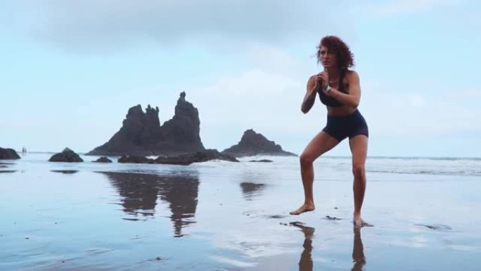 适合女性训练腿部与hiit锻炼跳跃深蹲锻炼。健身训练在夏季海洋白色沙滩上进行有氧运动，进行爆炸性的跳