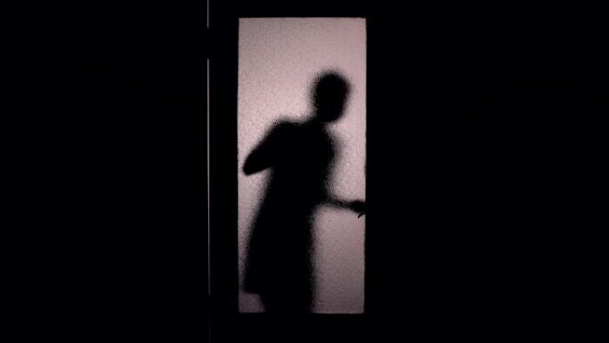 害怕的女人敲玻璃门的剪影检查把手，恐惧，逃跑
