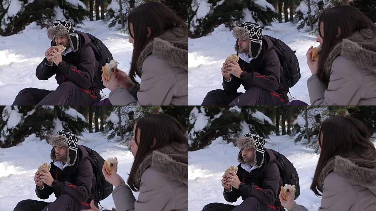 年轻夫妇在滑雪中休息一下，吃三明治