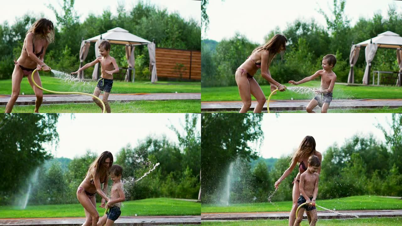 妈妈和儿子在草坪上玩，泼水，大笑，在操场上玩，在他的房子附近的湖边的草坪上