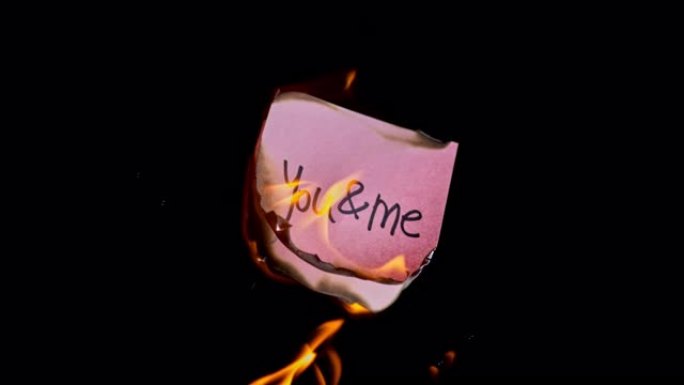 SLO MO LD粉红色的纸，上面刻有 “you & me” 字样，着火了
