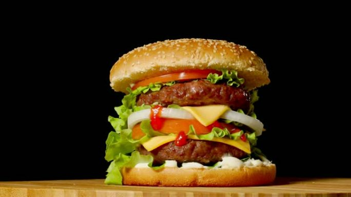 自制牛肉汉堡的特写镜头，生菜和蛋黄酱放在小木板上。深色背景