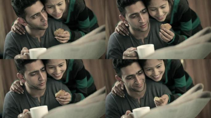 一对快乐的情侣一起看报纸，喝咖啡，吃零食。