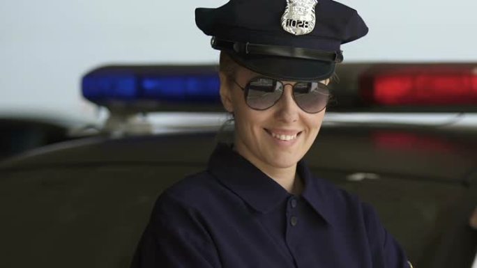 戴着帽子和墨镜的友好巡逻妇女对镜头微笑，法律保护