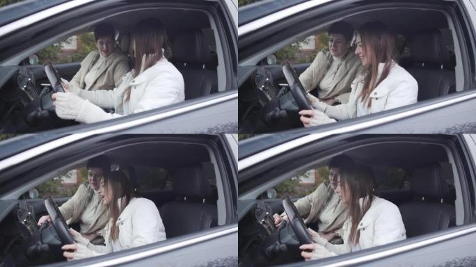 迷人的高加索母亲教成年女儿开车。快乐的黑发年轻女子坐在驾驶座上，拿着方向盘。