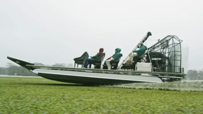 一艘汽艇在阴暗的天空下在路易斯安那州南部的Atchafalaya河流域沼泽中穿越漂浮的Salvini