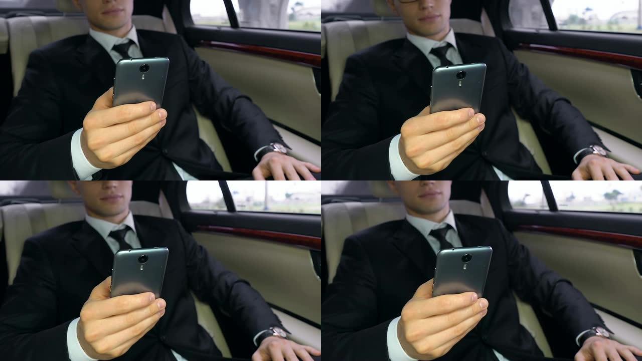 穿着西装的年轻人坐在汽车后座上使用智能手机，科技