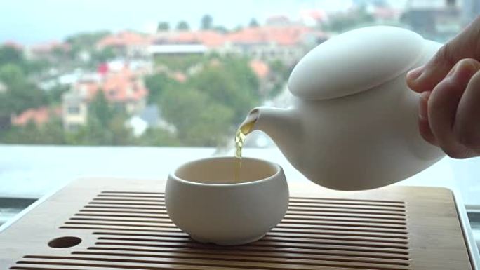 Hand pouring tea beside window