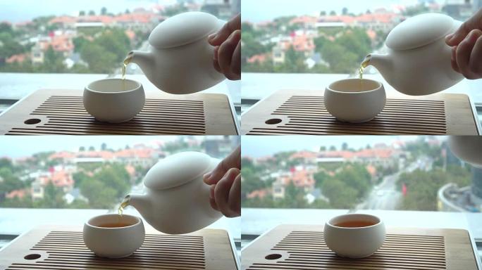 Hand pouring tea beside window