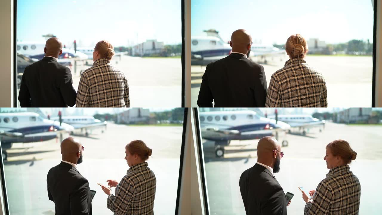 站在机场窗户前的同事的后视图