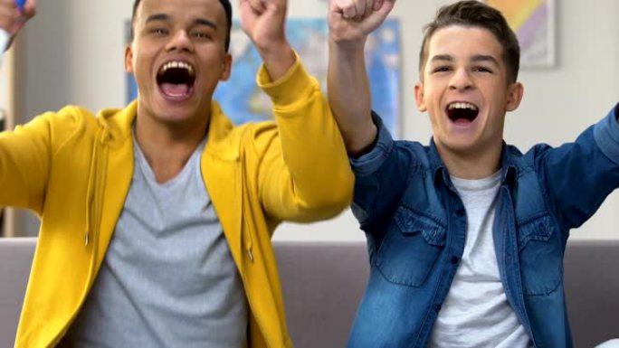 两名男性青少年在电视上观看足球比赛，高呼和吹喇叭