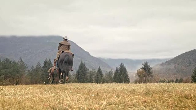 SLO MO两名牛仔在山上骑马