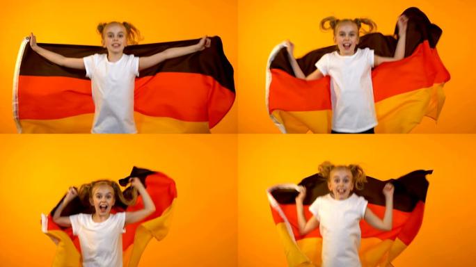 可爱的十多岁的女孩跳着德国国旗为最喜欢的运动队欢呼