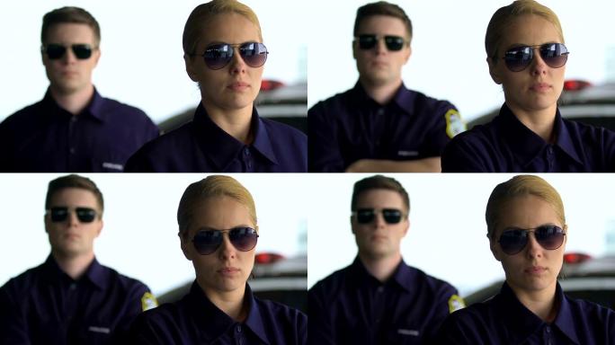 坚定的男警员和女警员戴着眼镜看着镜头，队伍