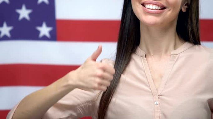 快乐的女性显示拇指特写美国国旗背景，移民