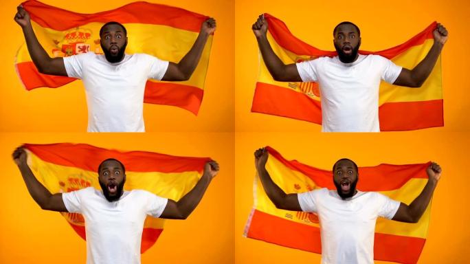 惊讶的非洲裔美国体育迷挥舞着西班牙国旗，为胜利欢呼