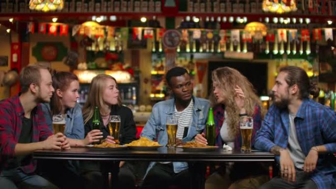 多种族的年轻男女在酒吧喝啤酒，并就大学进行有趣的讨论
