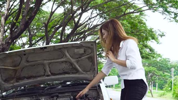美丽的亚洲女孩看发动机她的车坏了