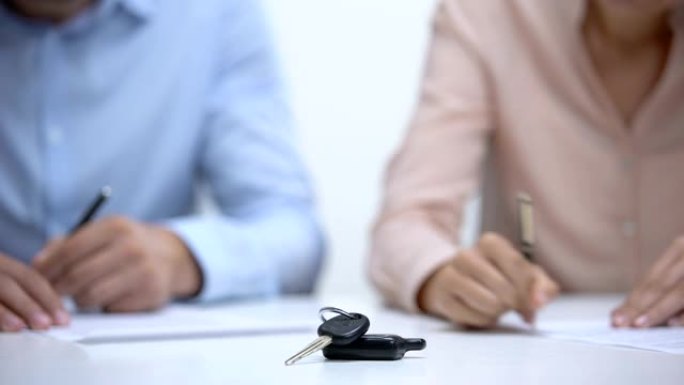 汽车钥匙特写，夫妇签署关于财产分割的离婚文件