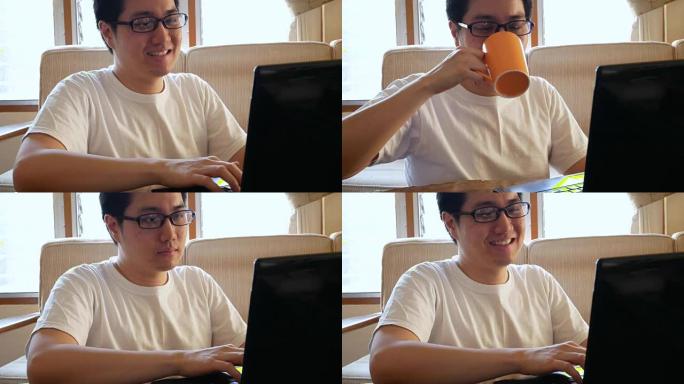 穿着休闲服的快乐亚洲男人在客厅用笔记本电脑喝咖啡-室内场景