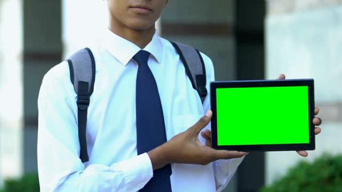 小学生展示带有绿屏的平板电脑，宣传电子书库应用程序