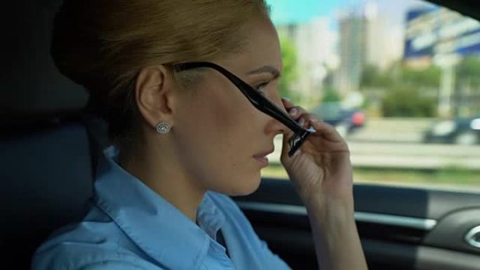 女人在开车时紧张地戴上眼镜，担心工作中的问题