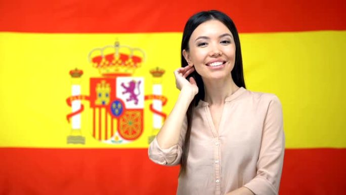 美丽的女人在西班牙国旗背景下看着相机，旅游