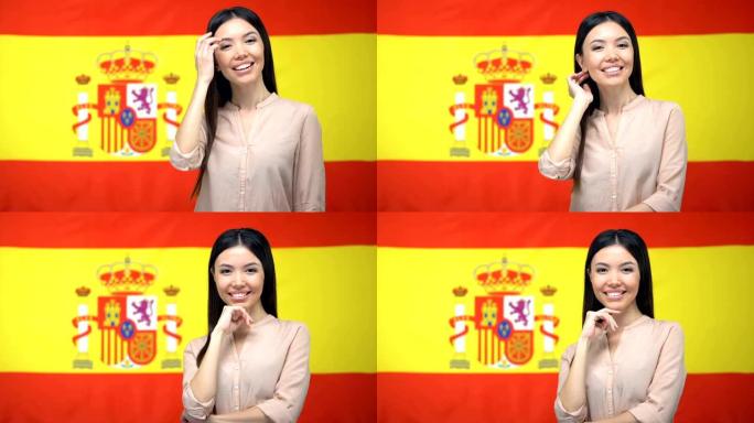 美丽的女人在西班牙国旗背景下看着相机，旅游