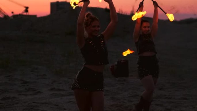 专业舞者的妇女在节日上用燃烧的闪闪发光的火炬进行火表演和烟火表演。