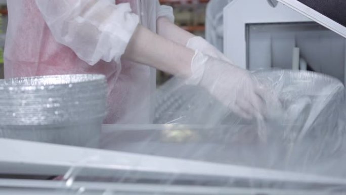 无法识别的高加索女工厂工人使用吸尘机包装成品。在工厂生产食品容器的职业女性。工业、商业。
