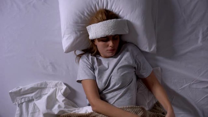 躺在床上受压的沮丧妇女，患有偏头痛，服用药丸