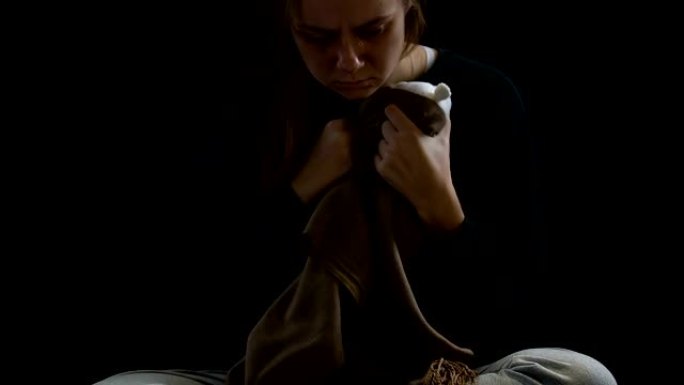 女人在围巾上哭泣的襁褓玩具，流产的痛苦，心理创伤